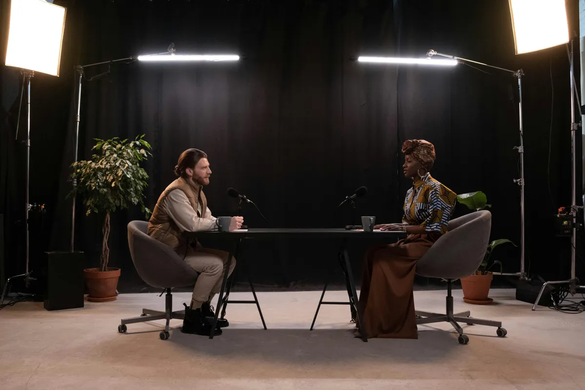 Two people recording a podcast across a table in a studio with professional lighting